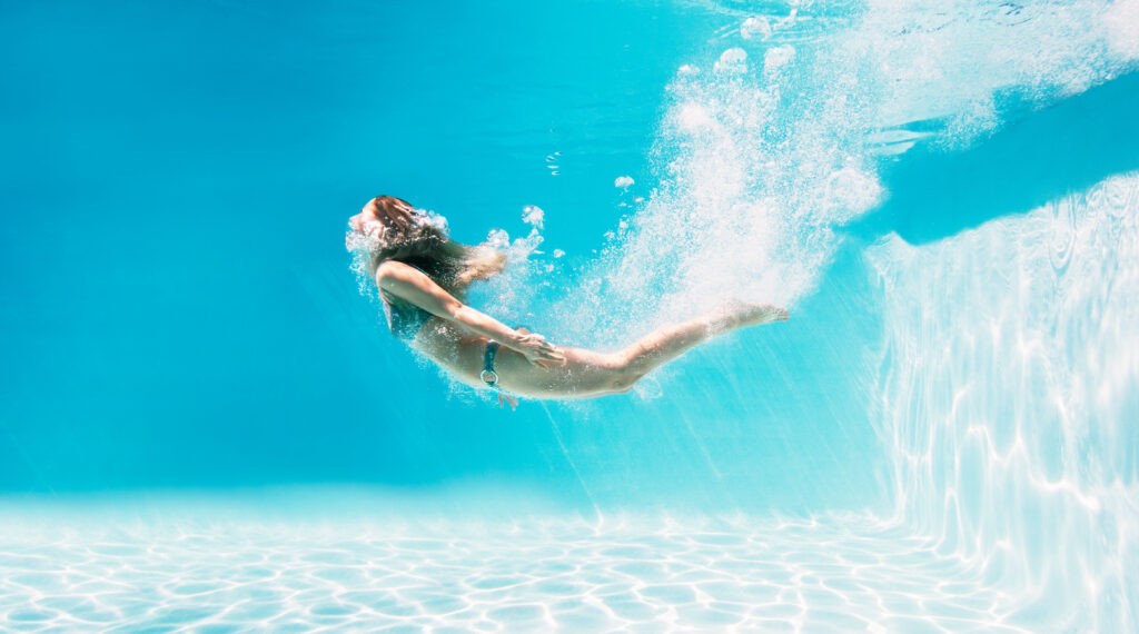 Woman enjoying a swim in a clear blue pool in Houston after healing from laser resurfacing treatment